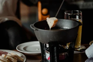 Utensil dipping in cheese dish