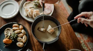 People dipping food with utensils in dip
