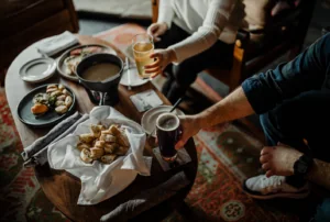 People holding drinks in front of table of appetizers
